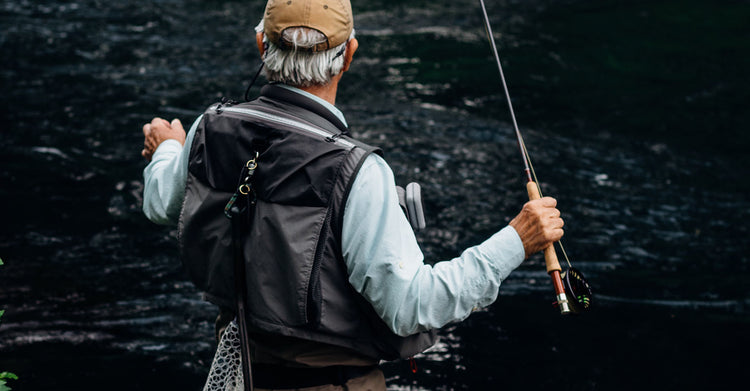 View of the back of a man fly fishing 